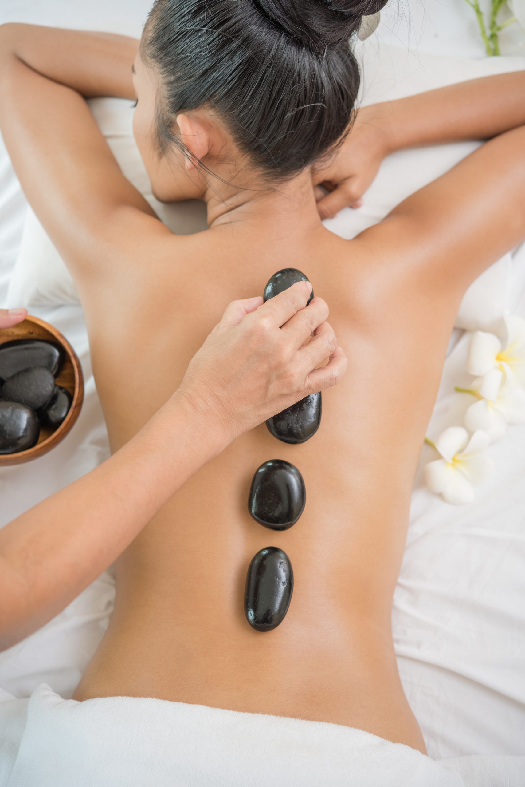 Young woman getting hot stone massage in spa salon. Beauty treatment concept.